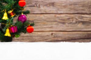 marco de navidad con árbol de navidad borroso y adornos y nieve y fondo de madera, espacio de copia. foto