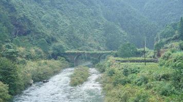 The beautiful Chinese countryside view with the old arched stone bridge above the river photo