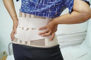 Asian senior wearing elastic support belt can help reduce back pain. photo