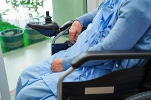 Asian elderly woman disability patient sitting on electric wheelchair in park, medical concept. photo