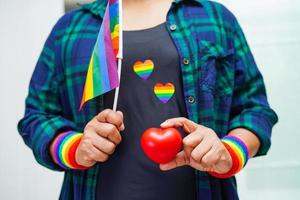 Asian woman holding red hert with rainbow flag, LGBT symbol rights and gender equality, LGBT Pride Month in June. photo