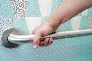 Asian woman patient use toilet support rail in bathroom, handrail safety grab bar, security in nursing hospital. photo