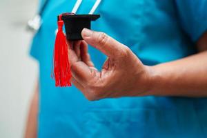 Asian woman doctor holding graduation hat in hospital, Medical education concept. photo