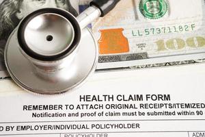 Health claim form with stethoscope and US dollar banknotes, insurance accident medical concept. photo