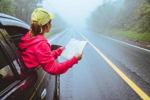 Asian women travel relax in the holiday. Traveling by car park. View map for Nature tours during the rainy season. photo