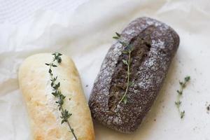 French baguettes with thyme on kraft paper. Mini baguette bread. Top view food, close up photo