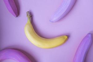 One yellow banana among colored pink bananas on pink background. Not such as all, unique concept. Closeup creative food pattern in minimal style. Flat lay, top view. photo