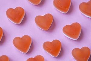 Red candy marmalade in shape of heart on pink background. Sugar gummy candy. Party food, Valentine's Day concept. Geometric pattern. Minimal design, flat lay, top view. photo