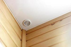 Fire alarm of fire detector on a ceiling. Smoke sensor in corner of room, wall of wood. Fire safety system photo