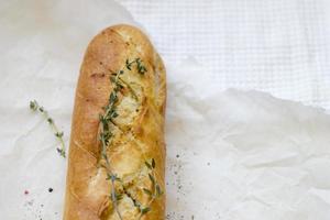 French baguettes with thyme on kraft paper. Mini baguette bread. Top view food, close up photo