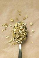 Oatmeal flakes and metal spoon on brown kraft paper. Concept of diet and healthy eating. Closeup vertical image in top view with copy space. photo