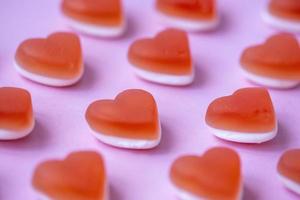 Red candy marmalade in shape of heart on pink background. Sugar gummy candy. Party food, Valentine's Day concept. Geometric pattern. Minimal design, flat lay, top view. photo