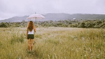 Asian women travel relax in the holiday. Running umbrella sunshine on a green pasture. photo