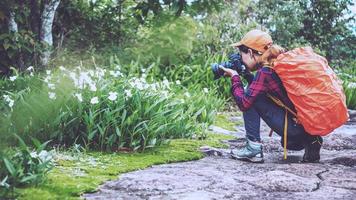 mujer asiática viaje naturaleza. viajar relajarse. caminar estudiar el camino naturaleza en el bosque. fotografía de flores foto