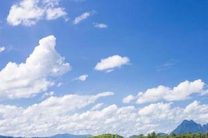 white clouds on blue sky and have the mountains in a down photo, clear sky in the afternoon, copy space of right on the photo. photo