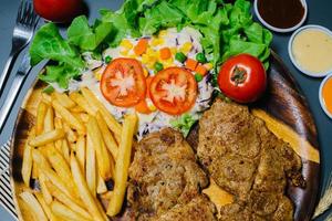 Grilled steak and lettuce, French fries on wooden plate photo