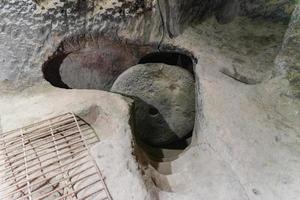 A round stone door in a cave. Cave of the 17th century Orthodox hermits. A narrow passage. photo