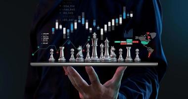 Businessman hold chess on tablet, investment strategy stock market concept. photo