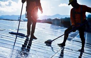 Photovoltaic technicians were cleaning and washing the surface of the solar panels which had dust and birds' pooping photo