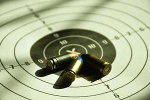 9mm bullets and 9mm bullet case on shooting target paper, soft and selective focus photo