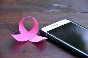 Pink ribbon on table with mobile phone. Concept for protesting and supporting the breast cancer against in woman. photo