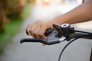 Closeup view of handlebar of bicycle which has hand of kid holding it. photo