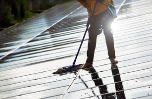 Photovoltaic technicians were cleaning and washing the surface of the solar panels which had dust and birds' pooping photo