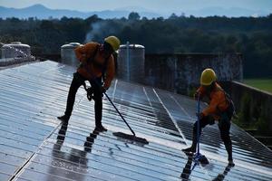 Photovoltaic technicians were cleaning and washing the surface of the solar panels which had dust and birds' pooping photo