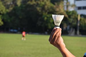 white badminton shuttlecock holding in hand. photo