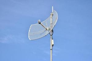 Outdoor internet wifi receiver and repeater antenna on the roof of the building with clear bluesky background. photo