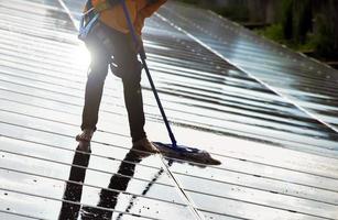 Photovoltaic technicians were cleaning and washing the surface of the solar panels which had dust and birds' pooping photo