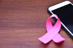 Pink ribbon on table with mobile phone. Concept for protesting and supporting the breast cancer against in woman. photo