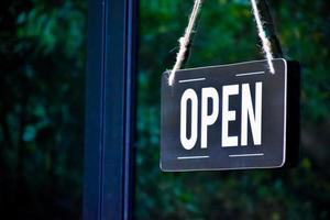 A shop label Open which hanging on the glass door of the shop, concept for informing people in Covid19 crisis situations around the world. photo