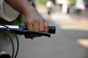 Closeup view of handlebar of bicycle which has hand of kid holding it. photo