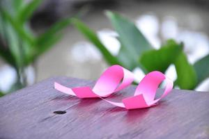 cinta rosa en la mesa de madera, concepto para luchar contra el cáncer de mama en mujeres de todo el mundo. enfoque selectivo y espacio de copia. foto