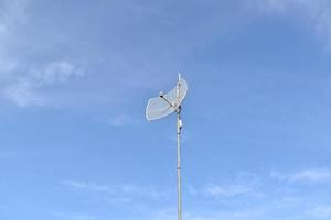 receptor wifi de Internet al aire libre y antena repetidora en el techo del edificio con un fondo azul claro. foto