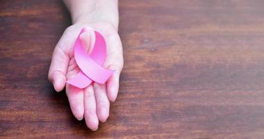 cinta rosa en la mano, símbolo de la campaña mundial contra el cáncer de mama en mujeres. foto