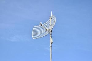 receptor wifi de Internet al aire libre y antena repetidora en el techo del edificio con un fondo azul claro. foto