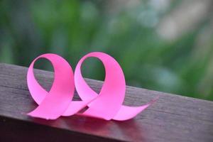 Pink ribbon on wooden table, concept for fighting against breast cancer in woman around the world. Selective focus and copy space. photo