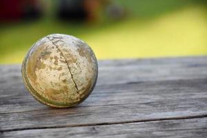 antiguos equipos deportivos de cricket de entrenamiento en suelo oscuro, pelota de cuero, wickets, casco y bate de madera, enfoque suave y selectivo, concepto tradicional de amantes del deporte de cricket en todo el mundo. foto