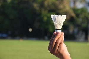 Volante de bádminton blanco sosteniendo en la mano. foto