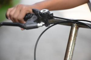 Closeup view of handlebar of bicycle which has hand of kid holding it. photo