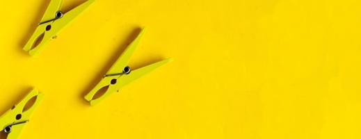 Top view, yellow clothespins on a yellow background, copyspace photo