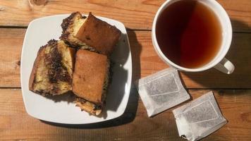 pastel de chocolate con una taza de té en tablero de madera. menú de desayuno por la mañana foto