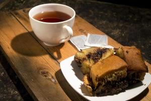 pastel de chocolate con una taza de té en tablero de madera. menú de desayuno por la mañana foto
