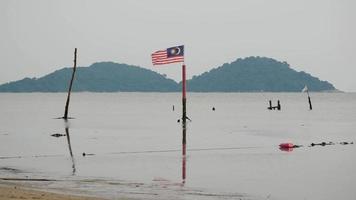 bandera de malasia jalur gemilang ola en la orilla del mar.