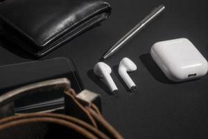 set of men's stuff on black background. smartphone, wireless earphone, leather belt, leather wallet and ballpoint pen photo