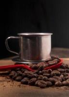 coffee beans on red spoon with stainless cup background photo