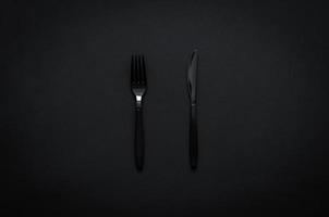 Fork and knife on dark background for minimalist flat lay black food concept. photo