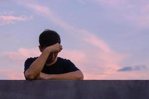 Asian miserable depressed man stay alone with sky background. Depression and mental health concept. photo